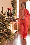 Woman carrying boxes of Xmas decorations through living room