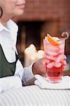 Woman on sofa holding glass of Campari with ice cubes