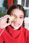 Girl holding cut-out biscuit in front of her eye