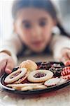 Girl reaching for plate of biscuits