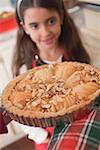 Hands holding apple tart, girl in background