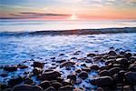 Wellen am felsigen Ufer im Morgengrauen, nahe Dunstanburgh Castle, Northumberland, England