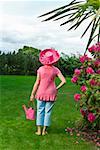 Femme en due forme chapeau rose festive dans le jardin