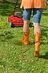 Woman mowing lawn with electric mower