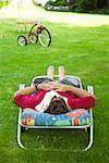 Mann mit Magazin über Gesicht Entspannung in Lounge-Sessel im Hinterhof