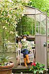 Woman drinking coffee in backyard greenhouse