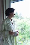 Woman drinking coffee and looking out window in the morning