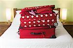 Two red suitcases stacked on a bed