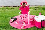 Woman in pink and dog picnicking by water