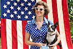 Patriotic woman and Boston Terrier dog posing with American flag
