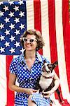 Patriotic woman and Boston Terrier dog posing with American flag