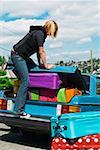 Woman loading car trunk with colorful suitcases