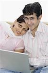 Portrait d'un couple d'adult mid à l'aide d'un ordinateur portable et souriant