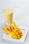 Gros plan d'une tranches de mangue dans un plat avec un verre de mango shake