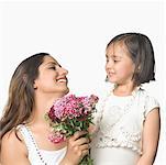 Close-up of a girl with her mother holding a bunch of flowers and smiling