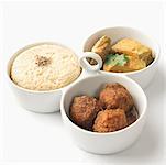 Close-up of boiled rice and meatballs with fish curry served in bowls