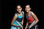 Portrait d'une jeune adolescente souriant avec sa sœur et la tenue des raquettes de badminton