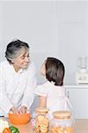 Girl looking at her grandmother preparing food