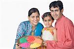 Portrait of a mid adult couple with their daughter holding a plate of powder paint and smiling