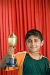 Portrait d'un garçon tenant un trophée et souriant