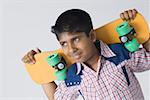 Close-up of a boy holding a skateboard and smiling