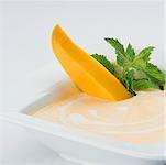 Bowl of cream with mango slices and mint leaves