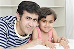 Portrait of a mid adult man with his daughter lying on the bed and smiling