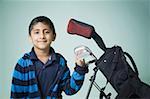 Portrait of a boy smiling beside a golf bag