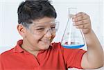 Close-up of a boy holding a conical flask and smiling