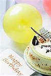 Close-up of a butterscotch cake with a birthday card and balloons