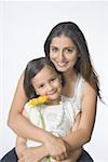 Portrait of a young woman hugging her daughter from behind and smiling