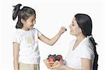 Close-up of a girl feeding fruits to her mother