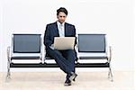 Businessman sitting on a bench and using a laptop