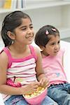 Girl eating popcorn beside her sister