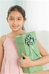 Portrait d'une jeune fille tenant un cadeau et souriant