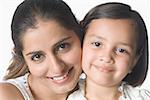 Portrait of a young woman cheek to cheek with her daughter and smiling