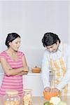 Mid adult woman looking at her husband preparing food