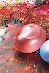 High angle view of two water bombs on multi-colored powder paint