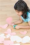 Side profile of a girl cutting papers in heart shape