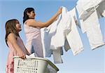 Low angle view of a mid adult woman and her daughter hanging clothes on a clothesline