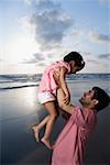 Side profile of a mid adult man playing with his daughter on the beach