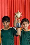 Portrait of two boys holding a trophy and smiling
