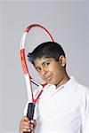 Portrait of a boy holding a tennis racket over his shoulder