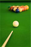 Close-up of a pool cue with pool balls on a pool table
