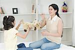 Mid adult woman and her daughter playing with a stuffed toy