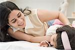 Close-up of a mid adult woman playing with her daughter on the bed