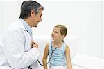 Girl listening to doctor's heart with stethoscope, smiling