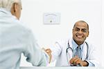 Doctor shaking hands with patient, smiling at camera, cropped