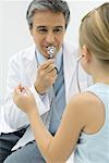 Pediatrician talking into stethoscope, girl listening