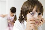 Little boy looking through magnifying glass at camera